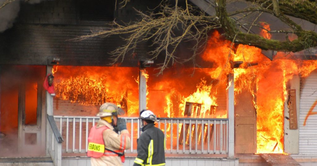 Fire fighters standing in front of house fire